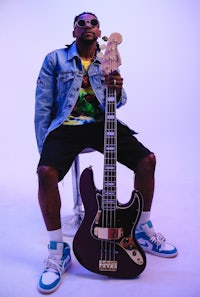 a man sitting on a stool holding a bass guitar