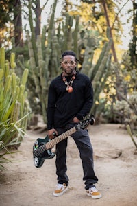 a man holding a guitar in front of cactus