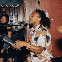 a man with dreadlocks singing into a microphone