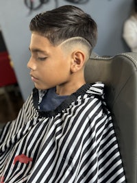 a young boy sitting in a barber chair